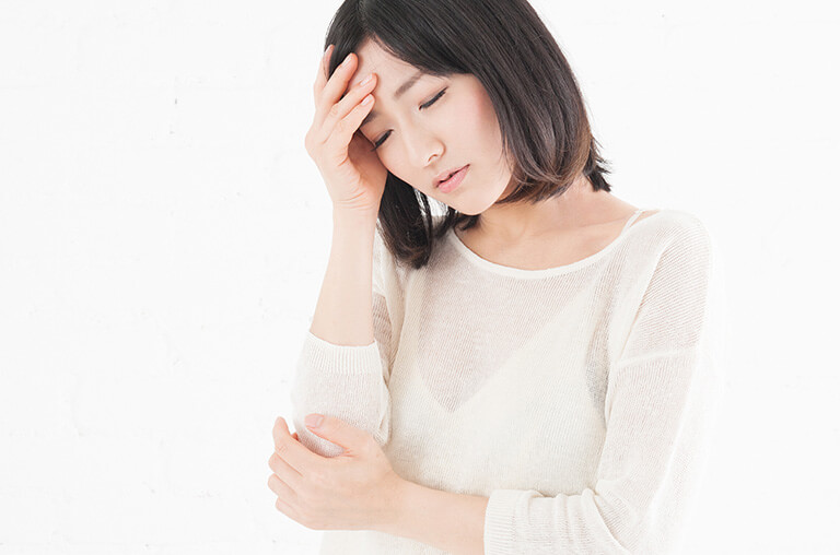 額に手をあてて首を傾げる女性